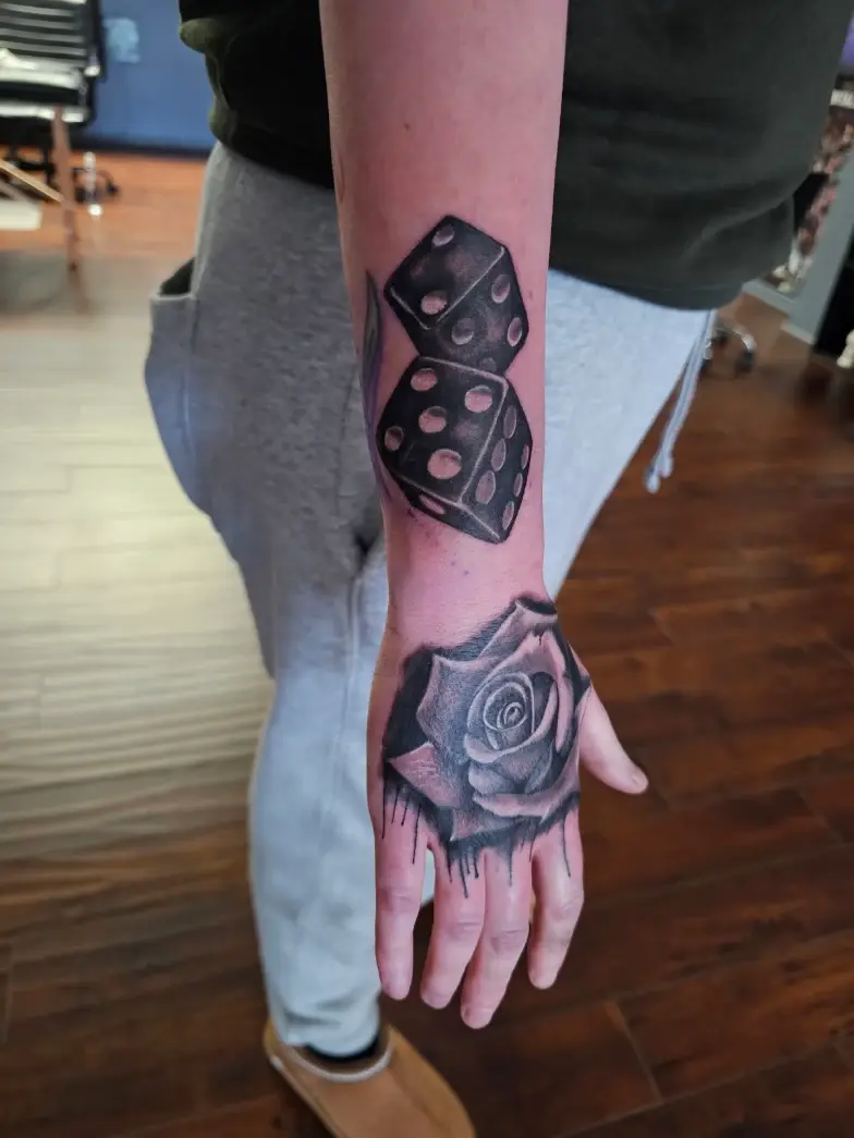 Dice and rose tattoo extending from the forearm to the hand